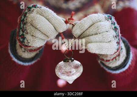 Le mani con i guanti di lana mostrano l'ornamento natalizio in cristallo Foto Stock