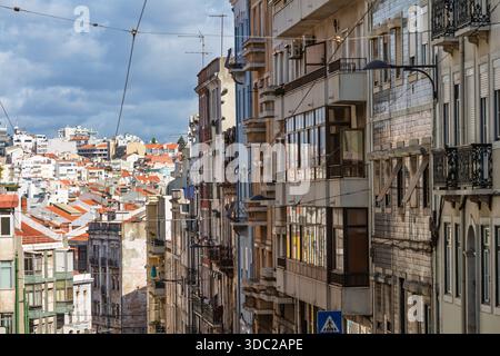 Teleobiettivo delle affollate facciate degli appartamenti a Lisbona, Portogallo, con molti balconi, finestre e tradizionali tetti rossi della città. Foto Stock