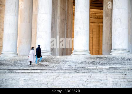 Jefferson Memorial Columns and Steps Washington DC // WASHINGTON DC - il Jefferson Memorial presenta le sue iconiche colonne di marmo bianco e ampi gradini, con due visitatori che salgono verso la struttura neoclassica. Dedicato a Thomas Jefferson, il terzo presidente degli Stati Uniti, il progetto del memoriale di John Russell Pope si ispira al Pantheon di Roma. Il monumento circolare all'aperto presenta 54 colonne ioniche. Costruito principalmente in marmo bianco Imperial Danby proveniente dal Vermont e dalla Georgia, fu completato nel 1943. Questo importante punto di riferimento si trova sul National Mall di Washington D.C. Foto Stock