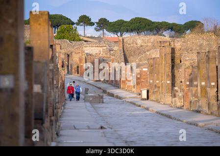 Via Pompei Italia, vista di turisti anziani che camminano tra le rovine di edifici in una strada nell'antica città di Pompei, Golfo di Napoli, Italia. Foto Stock