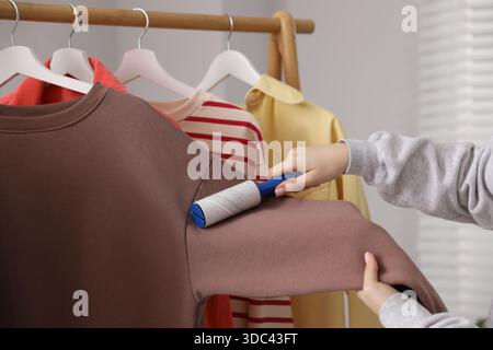 Donna che pulisce la felpa con rullo di lanugine a casa, primo piano Foto Stock