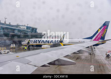 Ozarowice, Polonia - 23 novembre 2025: Una vista da un posto vicino al finestrino che guarda un aeromobile Ryanair Boeing 737 parcheggiato sull'asfalto bagnato di fronte al Foto Stock
