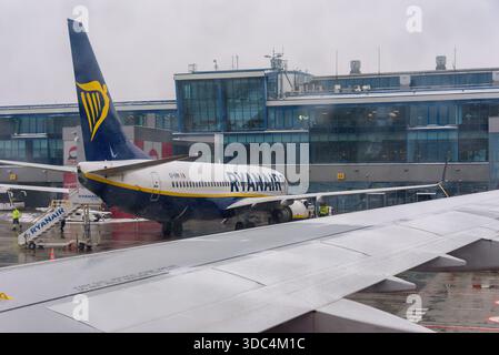 Ozarowice, Polonia - 23 novembre 2025: Una vista da un posto vicino al finestrino che guarda un aeromobile Ryanair Boeing 737 parcheggiato sull'asfalto bagnato di fronte al Foto Stock