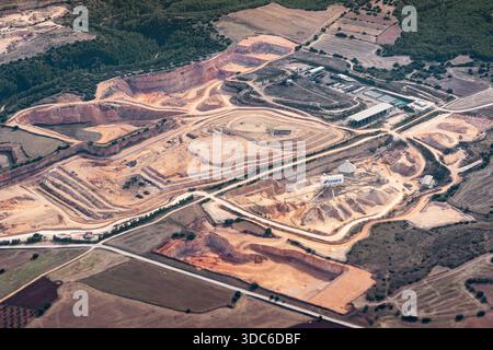 Vista aerea di una cava di cemento a cielo aperto gestita da CEMEX in Spagna, che mostra i livelli di scavo terrazzato, le strade di accesso e il paesaggio rurale circostante Foto Stock