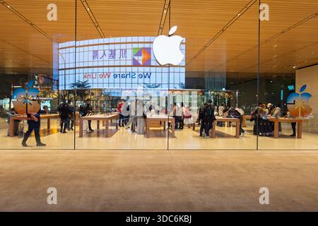 Taipei, Taiwan - 20 dicembre 2025: Vista interna dell'Apple Store attraverso la facciata in vetro con i clienti che navigano sui prodotti Foto Stock
