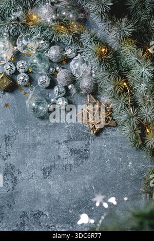 Varietà di giocattoli natalizi, palle d'argento e ghirlande illuminate sui rami di abete su sfondo blu. Piatto, spazio. Decorazioni di Natale e Capodanno o biglietto d'auguri. Foto Stock