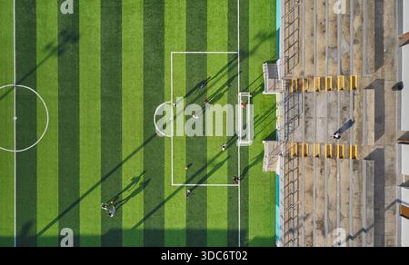 I giocatori di calcio si allenano su un campo di erba sintetica verde con lunghe ombre dall'alto Foto Stock