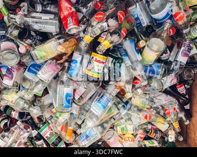 Stoccarda, Germania - 17 ottobre 2024: Pile di bottiglie e contenitori di vetro vuoti assortiti in vari colori e marchi che mostrano il potenziale di riciclaggio Foto Stock