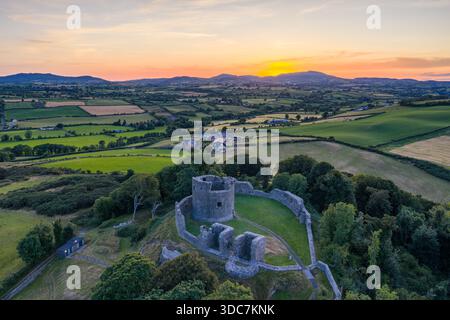 Una vista aerea mostra una valle illuminata dal sole di campi verdi e siepi, dominata dalle rovine medievali del castello, Dundrum, Irlanda del Nord Foto Stock