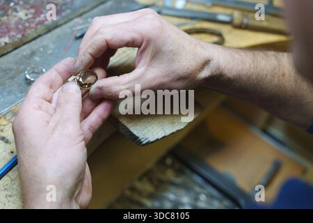 Gioielliere che ispeziona una pietra preziosa mentre lavora presso un banco di lavoro professionale in legno. Foto di alta qualità Foto Stock