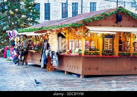Tallinn, Estonia - 3 dicembre 2025: Accogliente intimità invernale appare nelle bancarelle di legno del mercatino natalizio piene di luci calde, prodotti artigianali e stagona Foto Stock