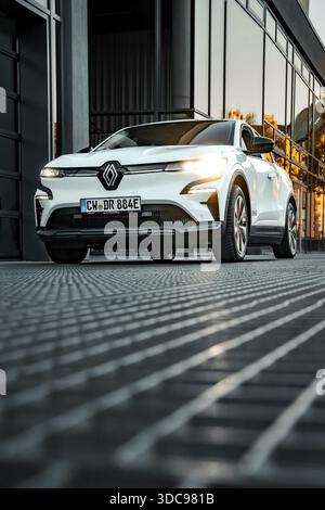 Renault davanti ai finestrini riflettenti al tramonto in ambiente urbano, Deer e-car sharing, Renault Megane, Calw, Germania Foto Stock