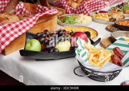 Frutta fresca e patatine fritte su un tavolo durante una riunione di cibo Foto Stock
