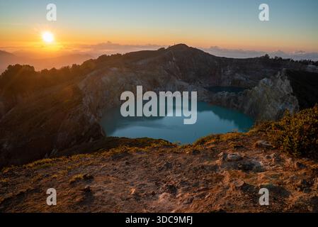 Il sole sorge su uno dei tre laghi multicolori del vulcano Kelimutu, il Parco Nazionale di Kelimutu, l'Isola di Flores, Indonesia Foto Stock