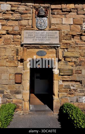 Porta in arenaria dorata a Palace Green, Durham, Inghilterra, Regno Unito, di Cosin’s Almshouses, costruito nel 1666 per il vescovo John Cosin per ospitare otto persone di sesso maschile e femminile. I residenti di Gowned frequentavano i servizi della cattedrale di Durham, pregavano due volte al giorno e dovevano vivere pacificamente, evitando il gioco d'azzardo e le taverne. Edificio, ora caffetteria-ristorante, ha sostituito le scuole di canto e grammatica fondate nel 1414 dal vescovo John Langley. Foto Stock