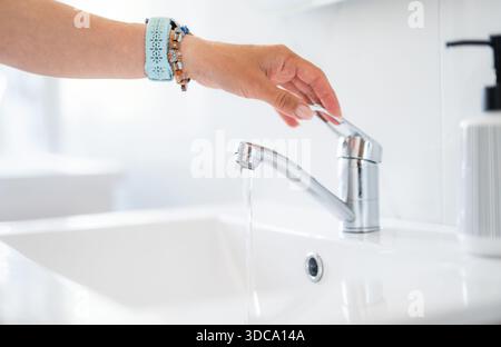 Woman's Hand spegne Faucet Water nel bagno di casa, primo piano Foto Stock