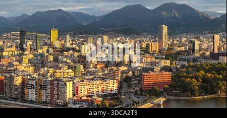 Un caldo panorama all'alba su Tirana, che mostra lo skyline della città, le torri moderne e il Monte Dajti che sorge dietro il fitto paesaggio urbano. Foto Stock