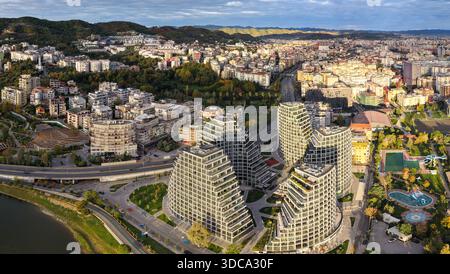 Ampio panorama aereo di Tirana con moderne torri residenziali, fitti quartieri urbani, parchi e quartieri collinari sotto la luce soffusa del mattino Foto Stock