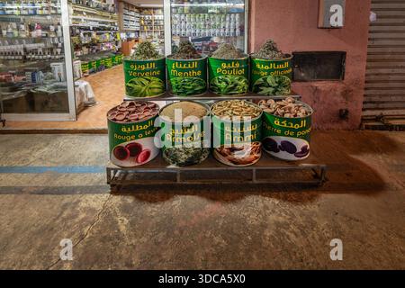 Vivace mercato di strada caratterizzato da grandi botti verdi piene di varie erbe e spezie, etichettate in arabo e francese. Un colorato e vivace menu Foto Stock