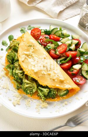 Frittata con broccoli arrostiti e formaggio servita con insalata di verdure fresche su piatto bianco su sfondo chiaro. Concetto di dieta sana. Chiudere u Foto Stock