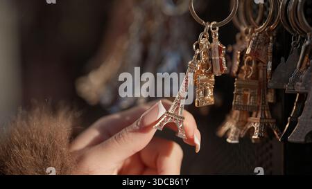 Primo piano di una mano che tiene una portachiavi della Torre Eiffel in un negozio di souvenir a Parigi in Francia l'immagine può essere utilizzata per viaggi turistici e cultura francese Foto Stock