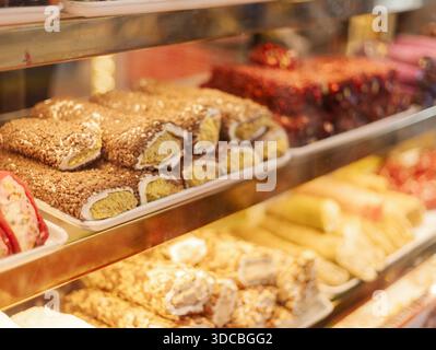 I dessert colorati sono ordinatamente disposti sugli scaffali. I clienti possono vedere diversi tipi di dolci, tra cui torte e pasticcini. Il negozio è ben illuminato e b Foto Stock