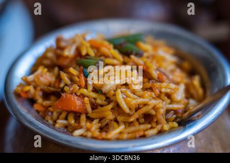 Biryani allo zafferano Navratico con verdure fresche, spezie e riso basmati in una pentola di metallo su fondo di legno, primo piano. Cucina indiana Foto Stock