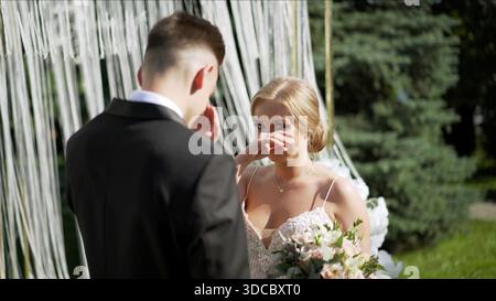 La sposa le strappa le lacrime dagli occhi. La sposa e lo sposo alla registrazione dell'uscita. Una sposa si pulisce una lacrima dall'occhio durante la cerimonia di registrazione Foto Stock