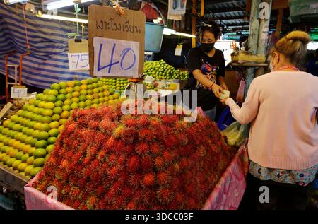 Bangkok, Thailandia - 15 luglio 2022: Venditori vendono rambutan e arance nel mercato Khlong Toei in mezzo a un elevato aumento dei prezzi. Foto Stock