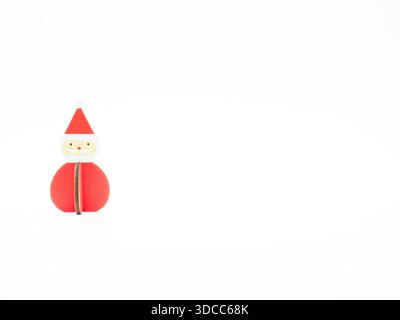 Una decorazione in legno di Babbo Natale in piedi sulla sinistra. Fotografato a livello degli occhi su uno sfondo bianco. Foto Stock
