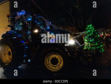 Trattore decorato con luci natalizie e un albero di Natale illuminato in una sfilata festosa notturna Tractors and Tinsel Run Devizes Wiltshire dicembre 2025 Foto Stock