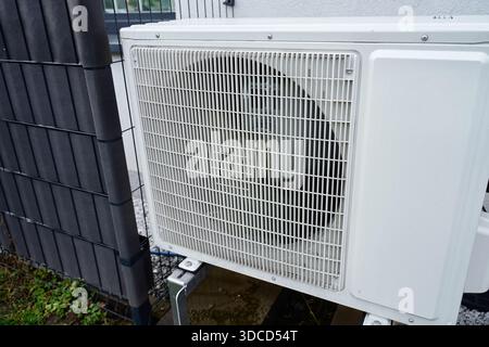 Primo piano della griglia di ventilazione sull'unità pompa di calore esterna con ventola rotante dietro il coperchio. Concetto di apparecchiature HVAC, riscaldamento a risparmio energetico e cooli Foto Stock