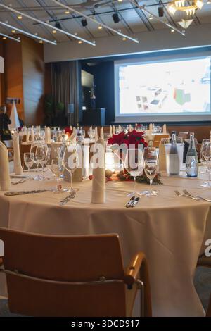 Un'elegante sala banchetti con tavoli decorati a festa e uno schermo di proiezione sullo sfondo, la festa di Natale del Dekra Congresshotel Wart, Calw dist Foto Stock