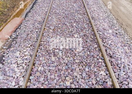 Primo piano di binari ferroviari ricoperti di ghiaia grigia e viola, costruzione della ferrovia Hermann Hesse, Calw, Germania Foto Stock