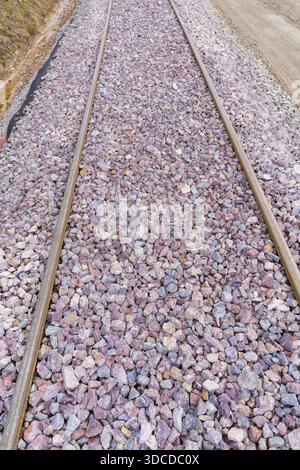Vista dettagliata dei binari della ferrovia densamente ricoperti di ghiaia grigia e viola, costruzione della ferrovia Hermann Hesse, Calw, Germania Foto Stock