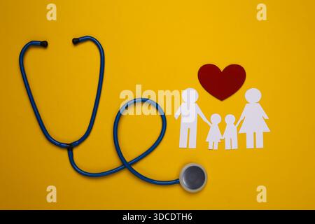 Stetoscopio e catena di carta famiglia, cuore rosso su sfondo giallo, concetto di assicurazione sanitaria Foto Stock