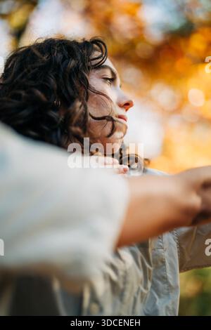 Donna che contempla l'esterno durante l'autunno con la luce del sole Foto Stock