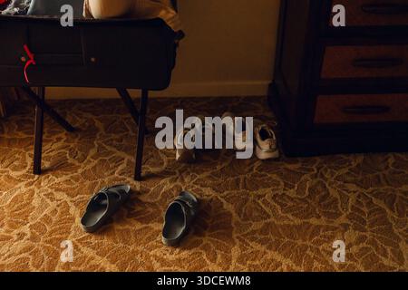 Scarpe appoggiate su moquette con luce calda della sera Foto Stock