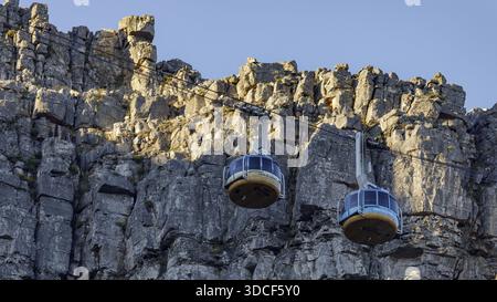 Città del Capo, Sud Africa - 25 novembre 2025: Vista delle funivie che si arrampicano contro l'aspra struttura della Table Mountain, bagnata dalla luce soffusa del sole. Foto Stock