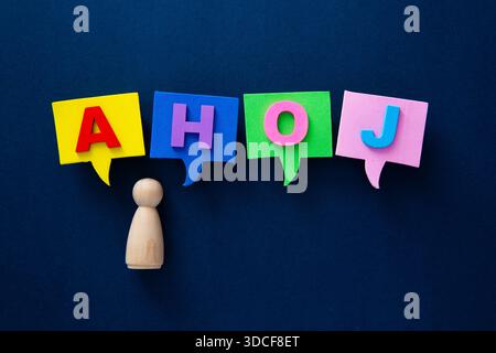 Figura in legno che parla ahoj in colorate bolle di schiuma su uno sfondo scuro Foto Stock