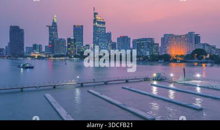 Vista aerea del fiume Saigon che riflette un vibrante paesaggio urbano con la Bitexco Financial Tower e il Landmark 81 che piergono il cielo crepuscolo, ho chi Minh Foto Stock