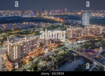 Vista aerea dei moderni appartamenti che si illuminano calorosamente lungo un fiume tortuoso, riflettendo le vivaci luci della città, ho chi Minh City, ho chi Minh City, Viet Foto Stock
