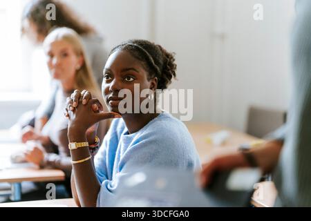 Giovane studentessa seduta con le mani schiacciate in classe al college Foto Stock