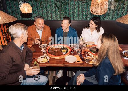 Vista dall'alto degli amici che si godono una cena al ristorante illuminato Foto Stock