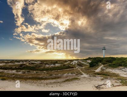 Una vista delle dune di sabbia e del faro di Dueodde sull'isola danese di Bornholm sotto un cielo espressivo Foto Stock