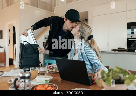 Giovane che bacia la fidanzata prima di partire per il lavoro Foto Stock