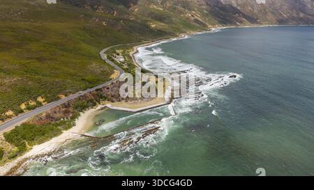 Vista aerea della costa frastagliata dove le onde oceaniche si scontrano con le coste rocciose vicino a Rooi-Els, Capo Occidentale, Sud Africa. Foto Stock