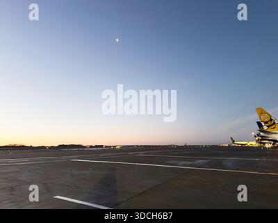 Manchester, Regno Unito - 13 dicembre 2025: Una vista del tramonto sull'asfalto dell'aeroporto di Manchester con aerei allineati al tramonto. Foto Stock
