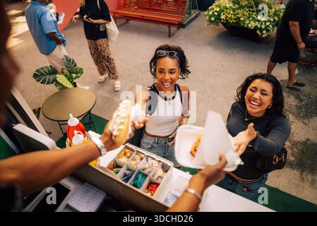 Vista ad angolo alto delle donne felici che acquistano spuntini al food truck Foto Stock