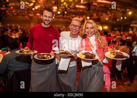 abb: David Biethig, Sascha Lauterbach und Victoria Herrmann als Promi Kellner beim Servieren von Teller mit Gaensekeuele Rotkohl und Kloesse bei der 31. Frank Zander Weihnachtsfeier Weihnachtsessen fuer Obdachlose und Beduerftige Menschen 2025 im Estrel Convention Center AM 22.12.2025 a Berlin Berlin Berlin Deutschland Foto Stock